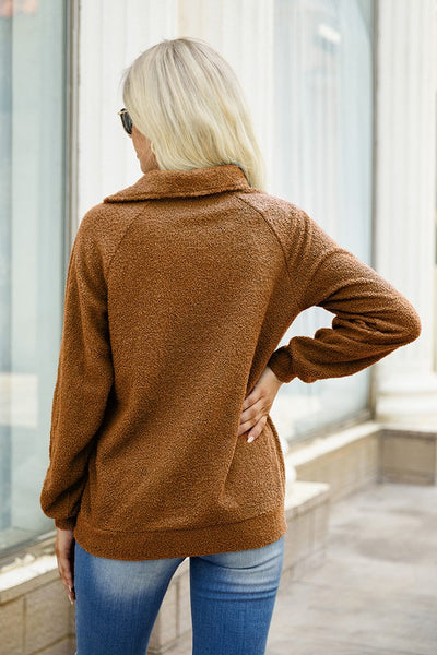Model presenting the back design of a taupe asymmetrical zipper neck sweater